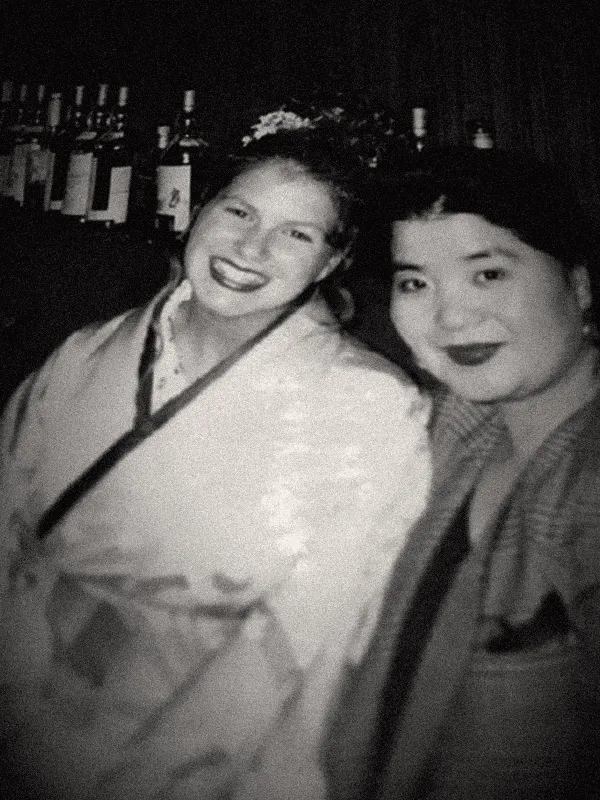 Fotografia antiga de Viviane sorrindo ao lado de uma mulher japonesa, em um bar.